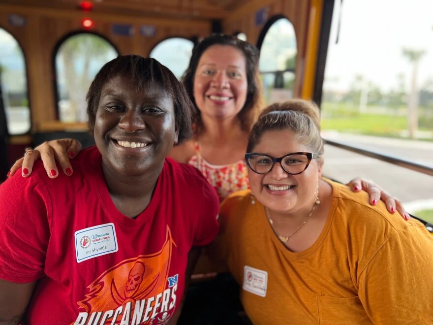 three women smile and sit on a cart