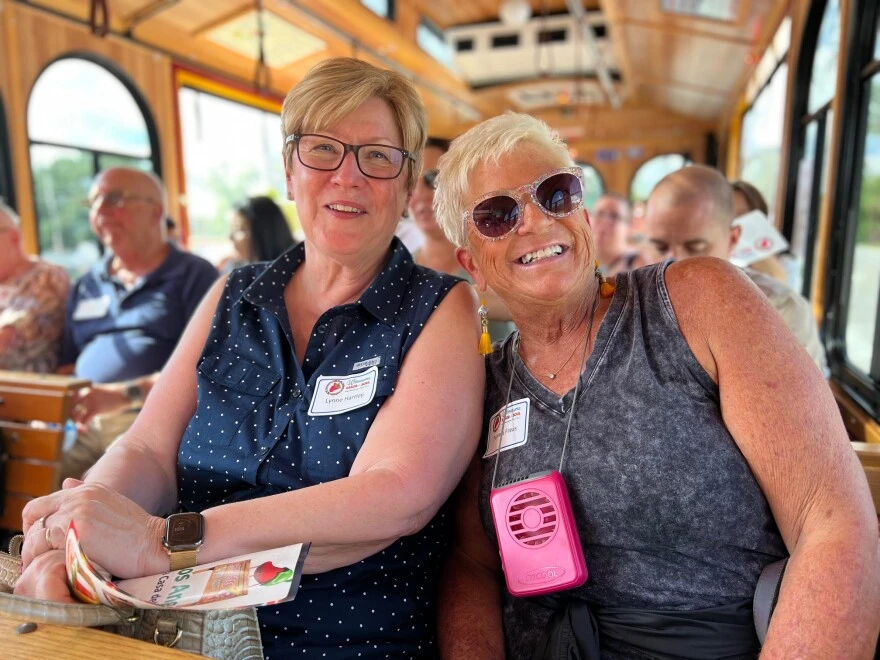 Two women smile together on a trolley