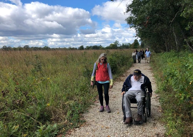 Walking along the trail and meadow at Elkhart Bog Nature Preserve, Elkhart County Parks Board Member Karen Mackowiak, left, and Ric Edwards, Director of ADA Compliance for the Department of Natural Resources from Indiana.